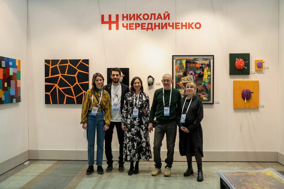 Участники ярмарки у стенда художника